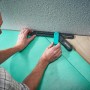 Mann benutzt wolfcraft Verlege-Set für Vinylboden an einer Ecke.
