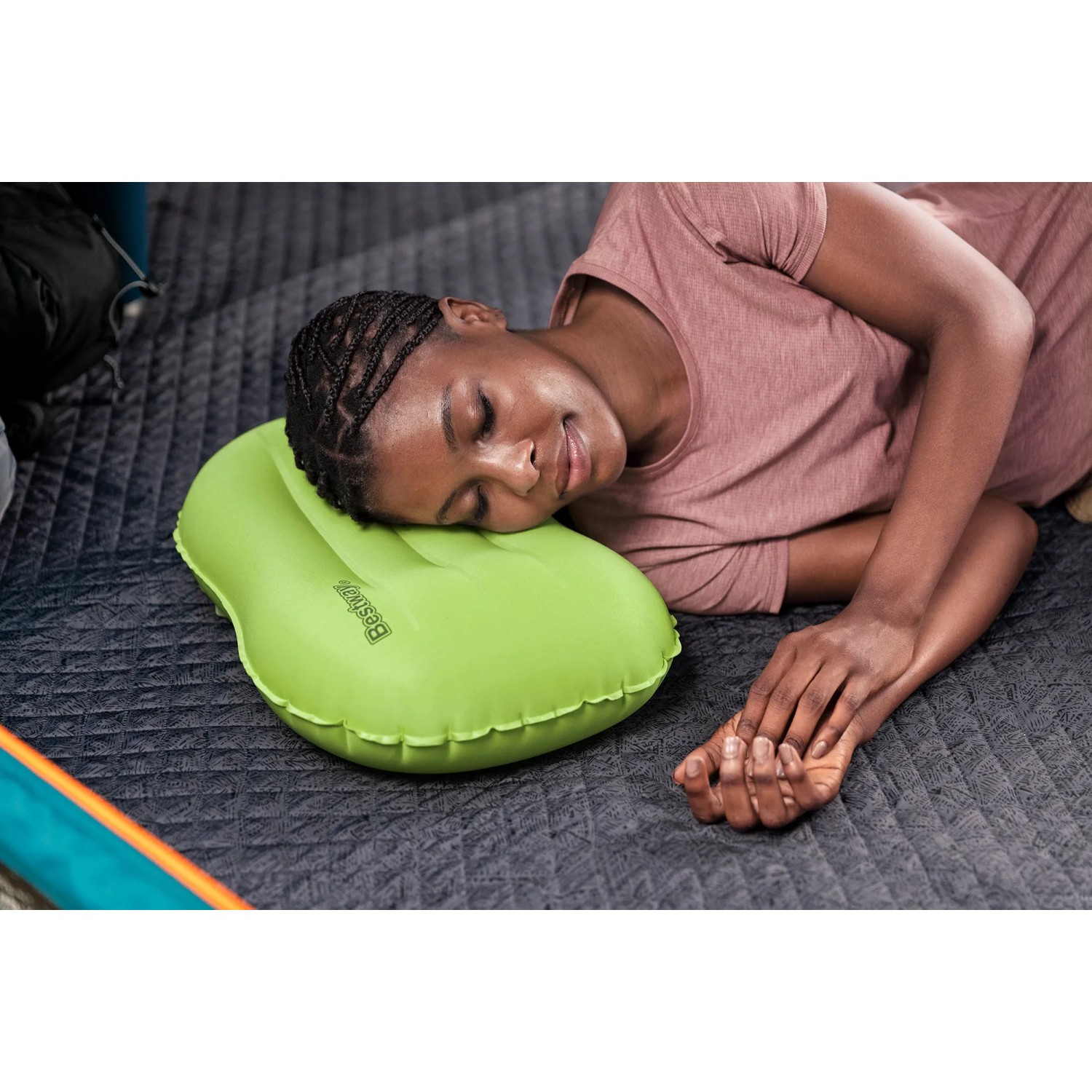 Frau schläft auf grünem Bestway Air Pillow Wanderlite Camping-Kissen.