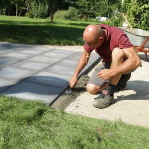 Handwerker beim Verarbeiten von Sakret Betonspachtel zum Verfugen von Pflastersteinen im Außenbereich.