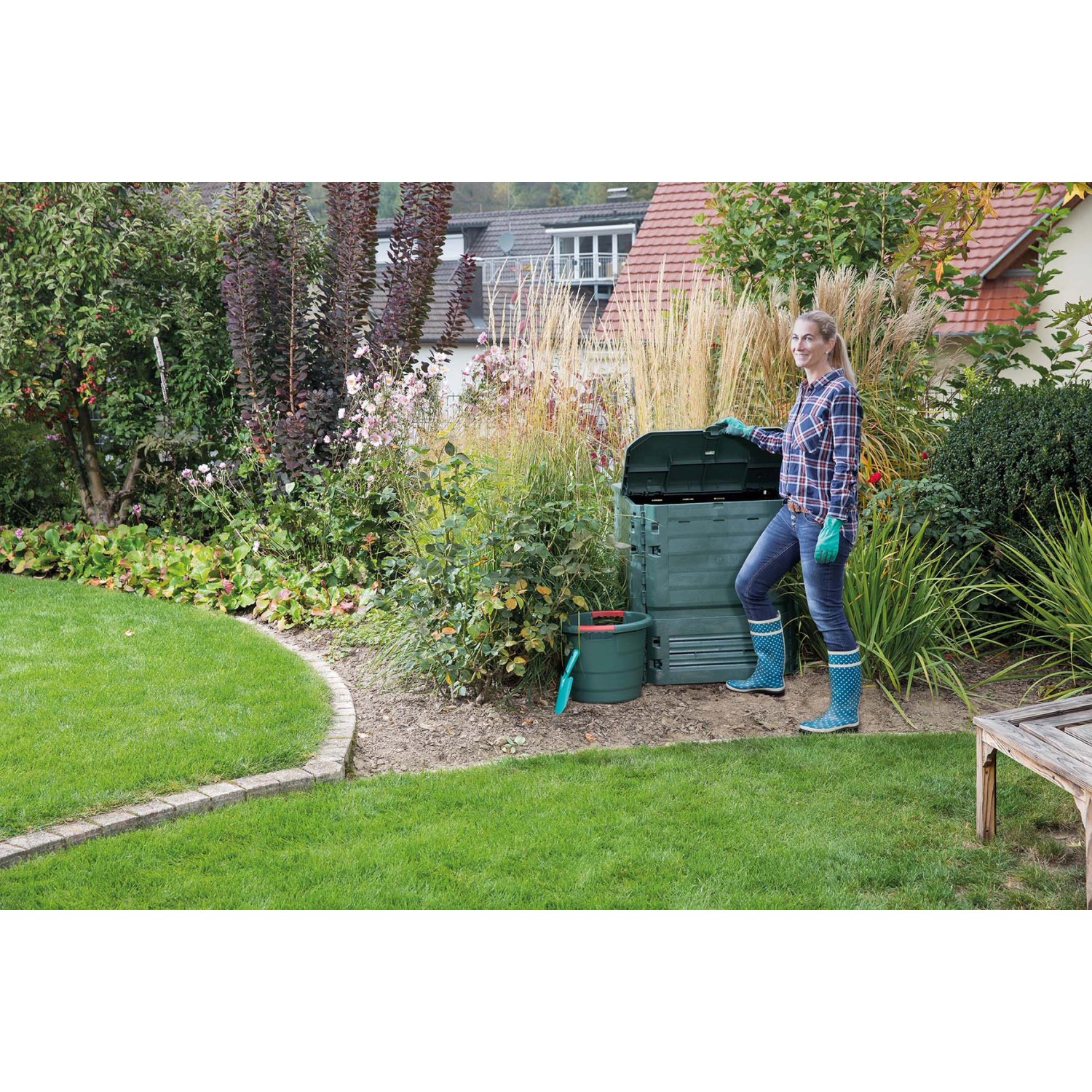 Garantia Thermokomposter Thermo-King 900 l grün im Garten mit Frau. Kompostierung von Gartenabfällen.
