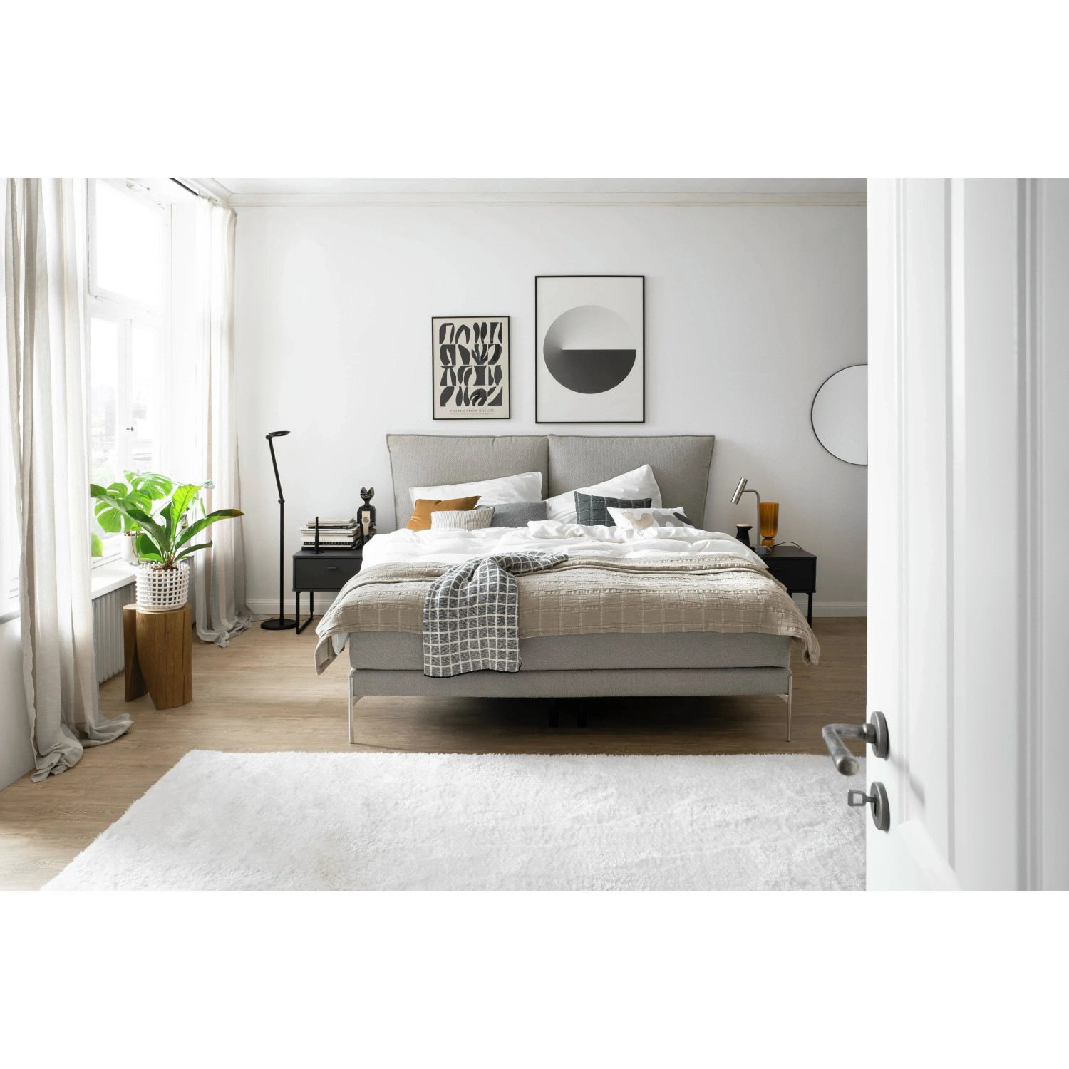Schlafzimmer mit Bett, Teppich und Vorhängen vor Fenster. Dekorative Elemente im Raum.