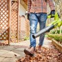 Mann nutzt Ryobi Akku-Laubgebläse RY18BLA-140 One+ zum Laub entfernen im Garten.