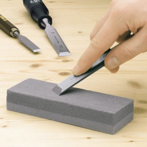 LUX Schleifstein Classic mit Beitel auf Holzuntergrund. Werkzeug zum Schärfen von Hobel und Beitel.