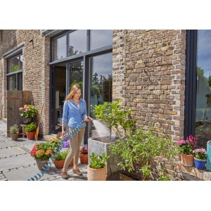 Frau bewässert Pflanzen mit Gardena Spiralschlauch-Set (10 m) im Garten.