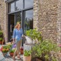 Frau bewässert Pflanzen mit Gardena Spiralschlauch-Set (10 m) im Garten.