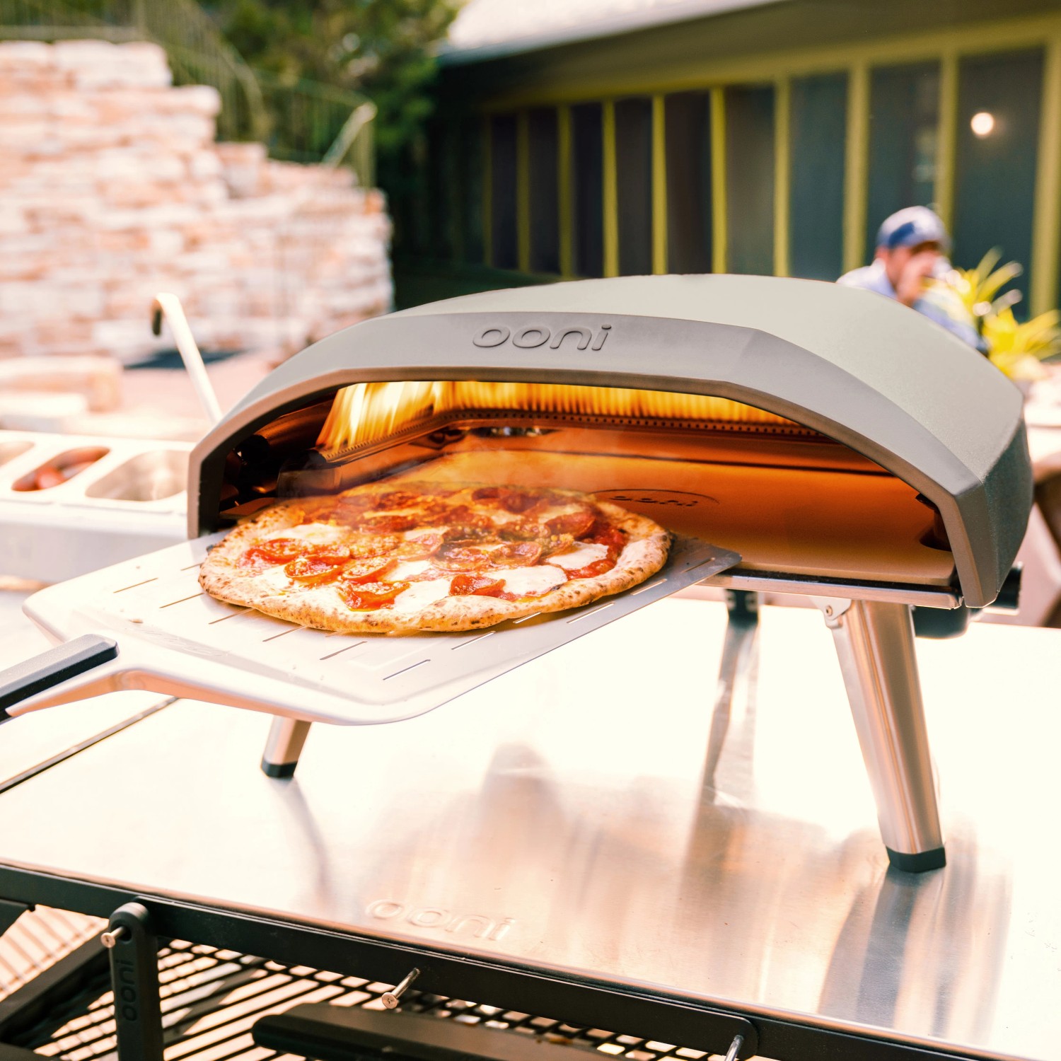 Ooni Koda 16 Gas Pizzaofen mit Pizza auf Pizzaschieber vor dem Ofen.