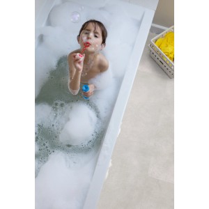 Kind in Badewanne mit Gerflor Vinylboden in Betonoptik. Feuchtraumgeeignet.