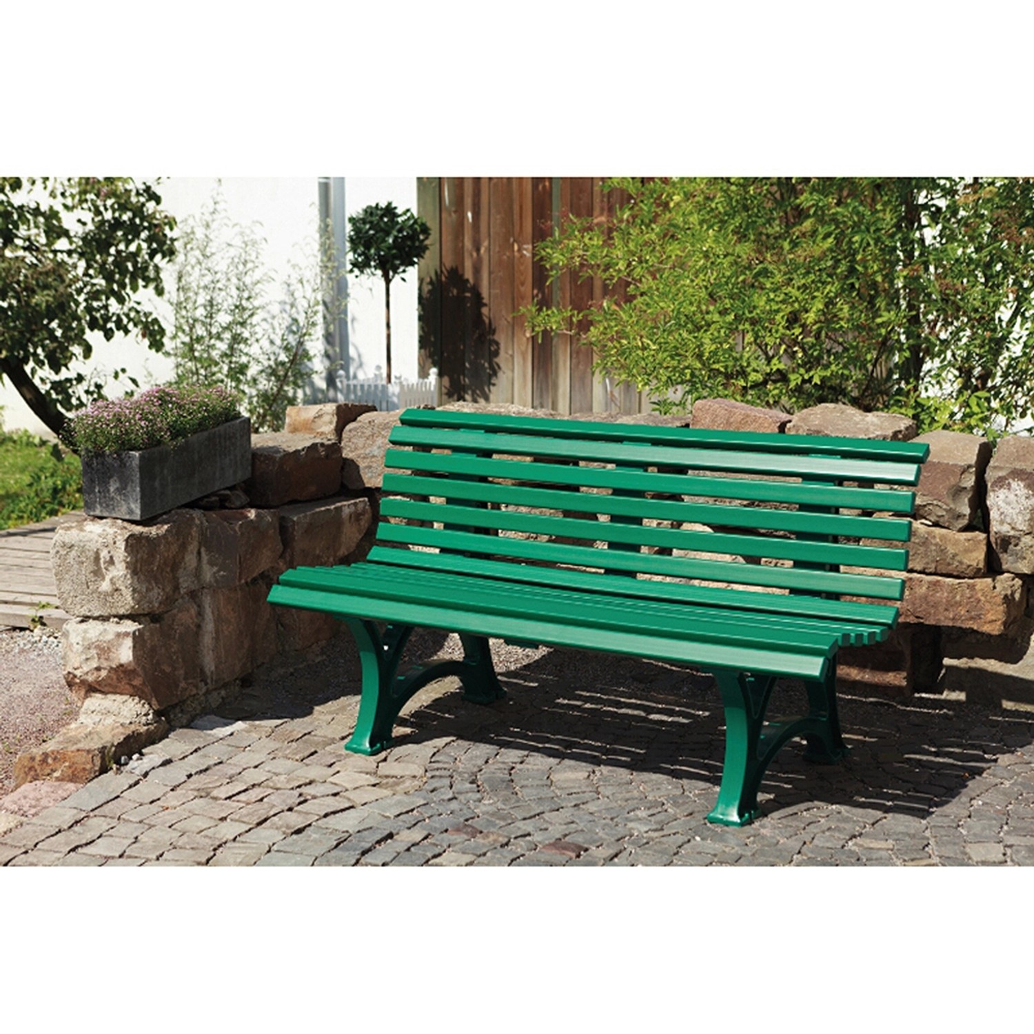 Grüne Blome 3er Gartenbank Helgoland, 150 cm breit, vor Steinmauer und Grünpflanzen.