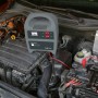 Batterie-Ladegerät 12A beim Aufladen einer Autobatterie im Motorraum.