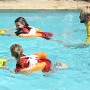 Kinder mit Freds Swim Academy Schwimmreifen Classic Orange und Schwimmbrett im Pool.
