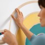 Frau klebt mit Tesa Malerband Kurven ein Wandbild ab.