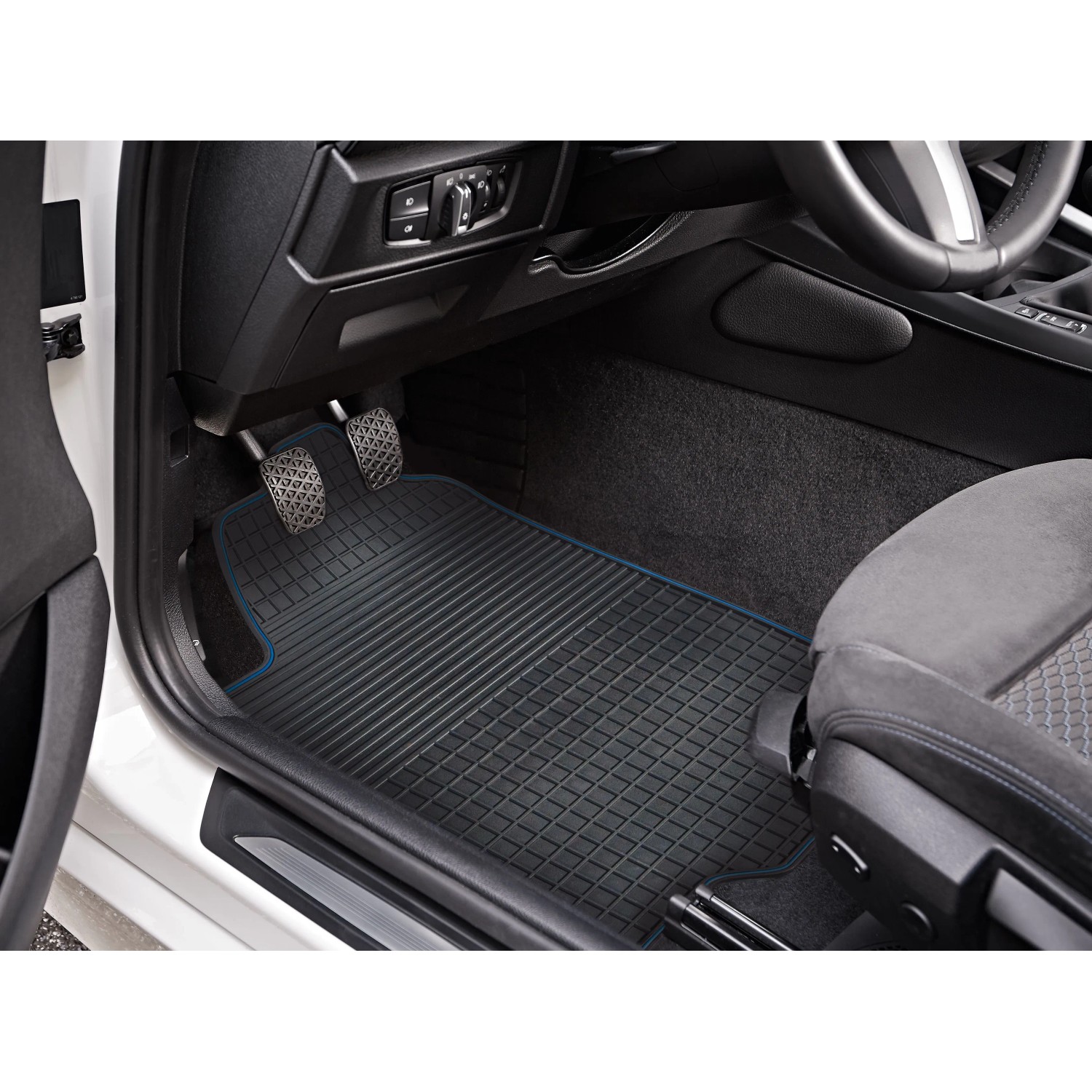 Schwarze OBI Fußmatten mit blauem Rand im Fußraum eines Autos.