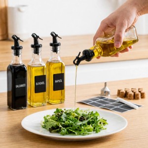 Relaxdays Ölflaschen Set: Transparente Glasflaschen mit schwarzen Ausgießern, eine gießt Öl auf Salat. Für Küche & Geschirr.