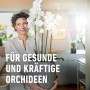 Frau hält Topf mit blühenden Orchideen, Compo Sana Orchideenerde für gesunde Pflanzen.