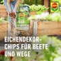 Frau streut Compo Bio Eichendekor-Chips als Unkrautbarriere in ein Hochbeet.