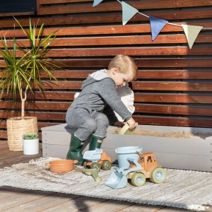 Kind spielt im warmgrauen MUDDY BUDDY Sandkasten Space Saver mit Spielzeugbagger.