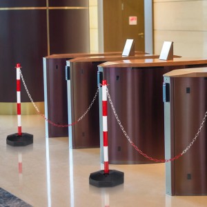 Zwei rot-weiße Kunststoff Absperrpfosten mit Kette auf hellem Boden. Ideal für mobile Absperrungen bei Events und Veranstaltungen.