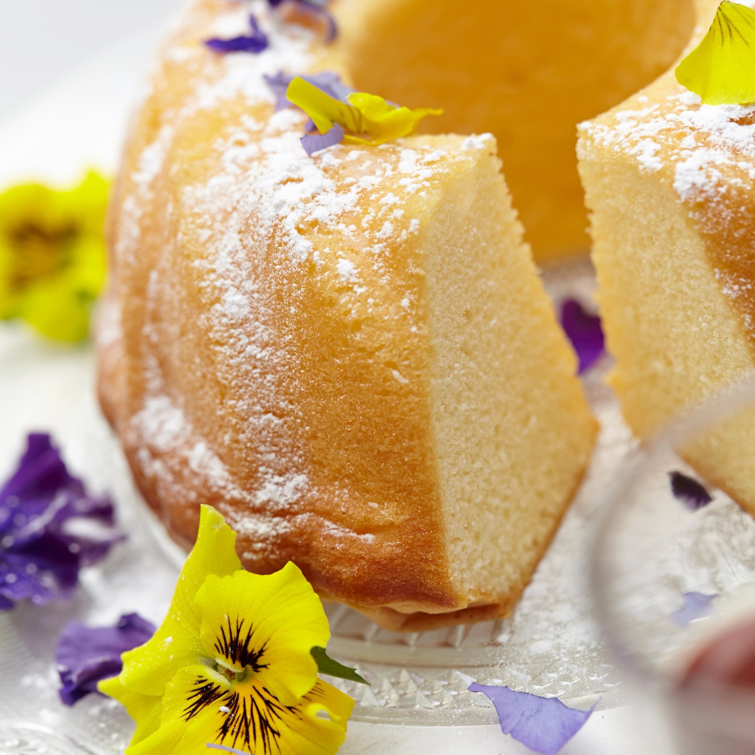 Kuchen mit Puderzucker und Blu Bio-Stiefmütterchen Blüten dekoriert.