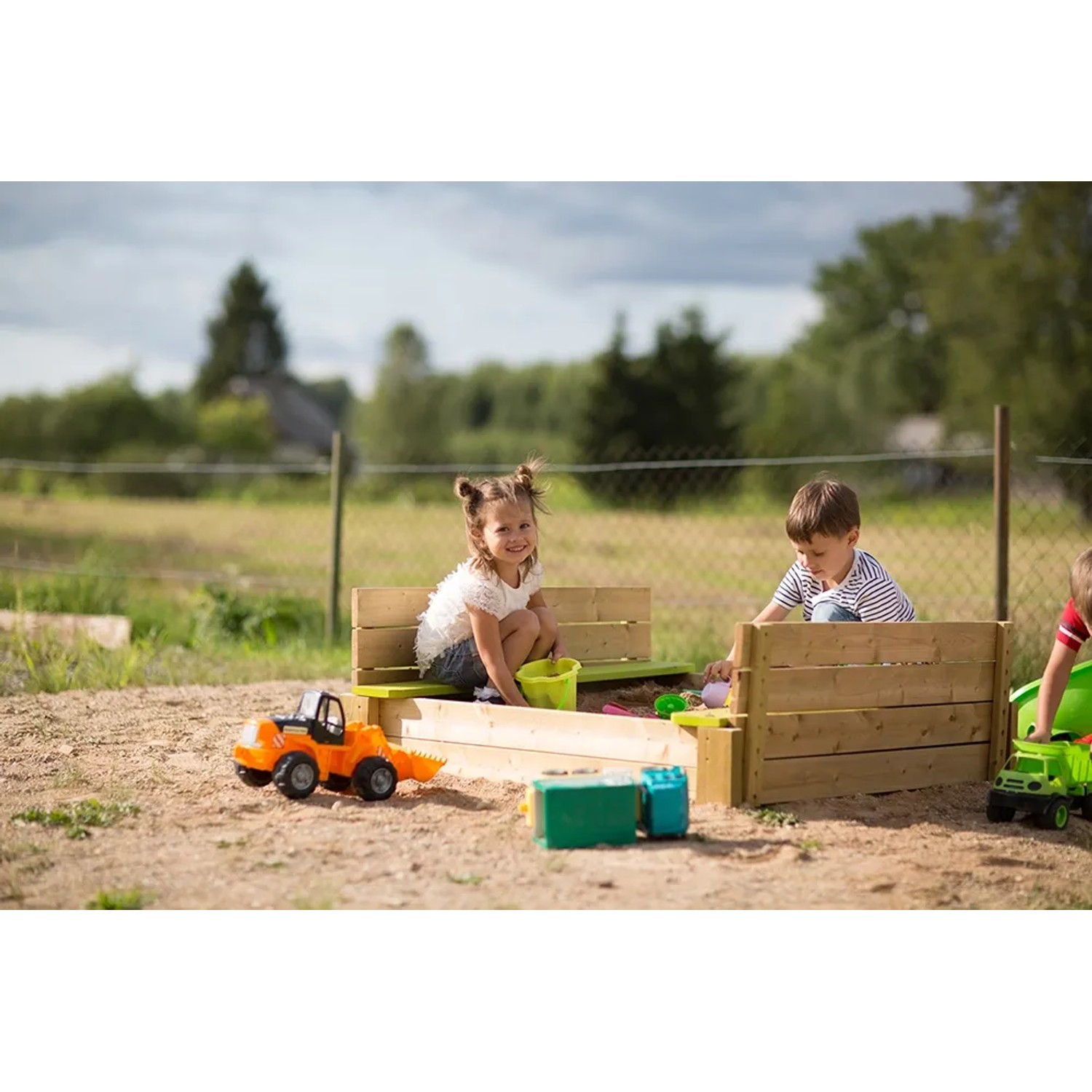 Wendi Toys Sandkasten mit Holzabdeckung und Sitzflächen, bespielt von Kindern im Garten.