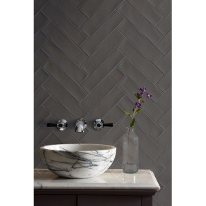 Wandfliese Artisa Carbon glänzend, 7,5x30 cm, im Fischgrätmuster an der Wand.