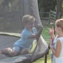 Grünes EXIT Silhouette Trampolin (D305cm) mit zwei Kindern im Garten.