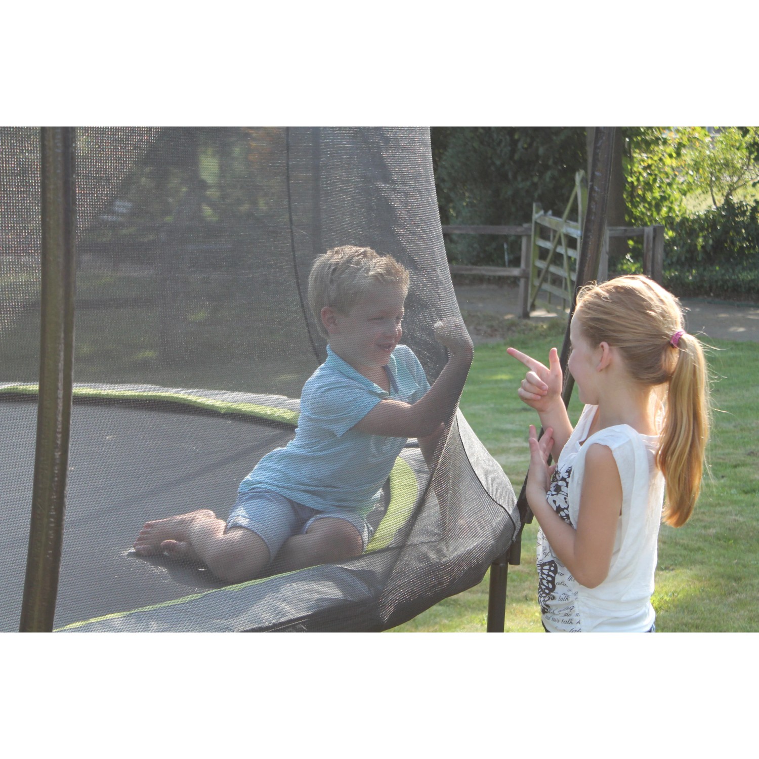 Grünes EXIT Silhouette Trampolin (D305cm) mit zwei Kindern im Garten.