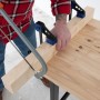 Handwerker sägt Holz auf der rikta Werkbank 159 cm. Stabile Werkbank mit Holzplatte und Schraubzwingen.