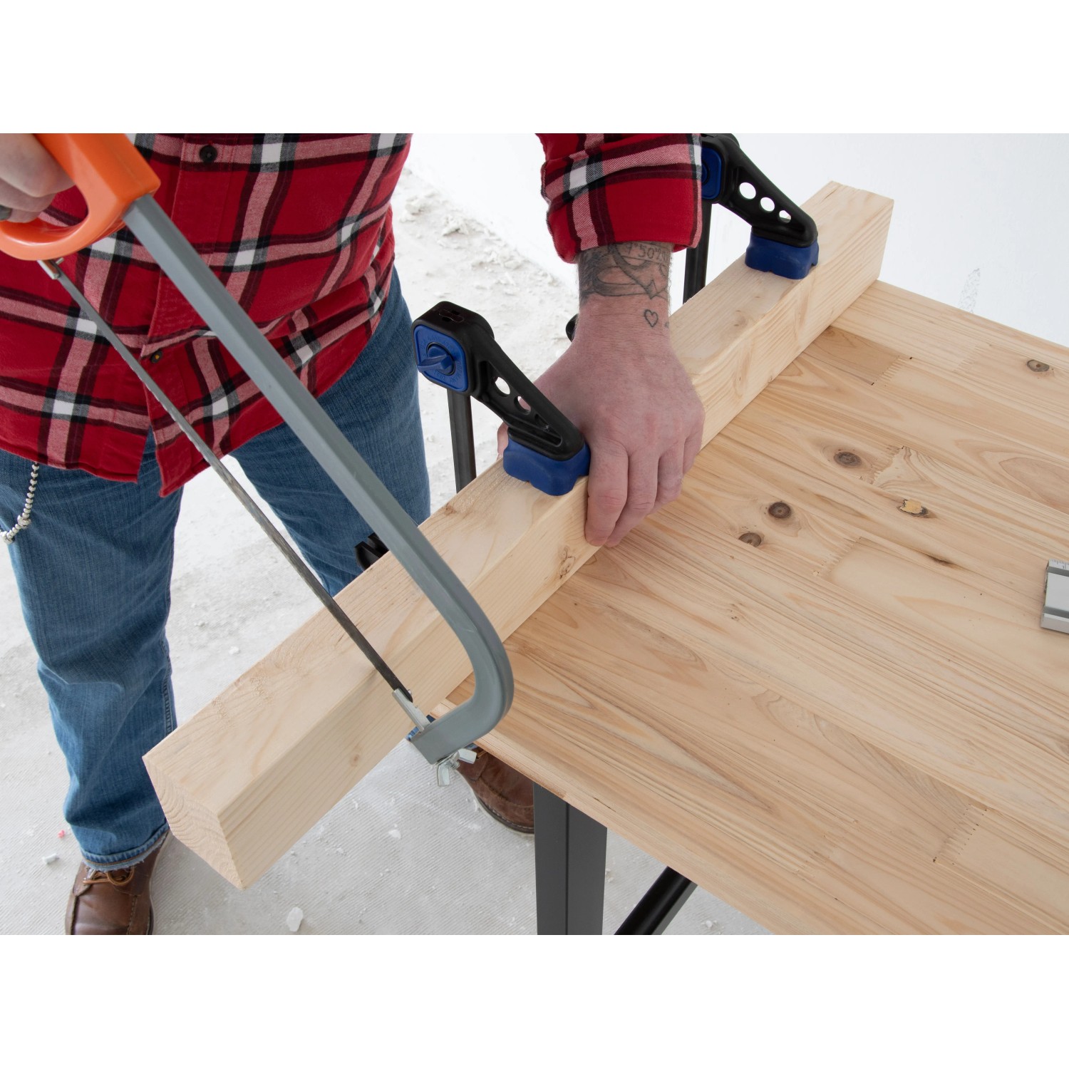 Handwerker sägt Holz auf der rikta Werkbank 159 cm. Stabile Werkbank mit Holzplatte und Schraubzwingen.