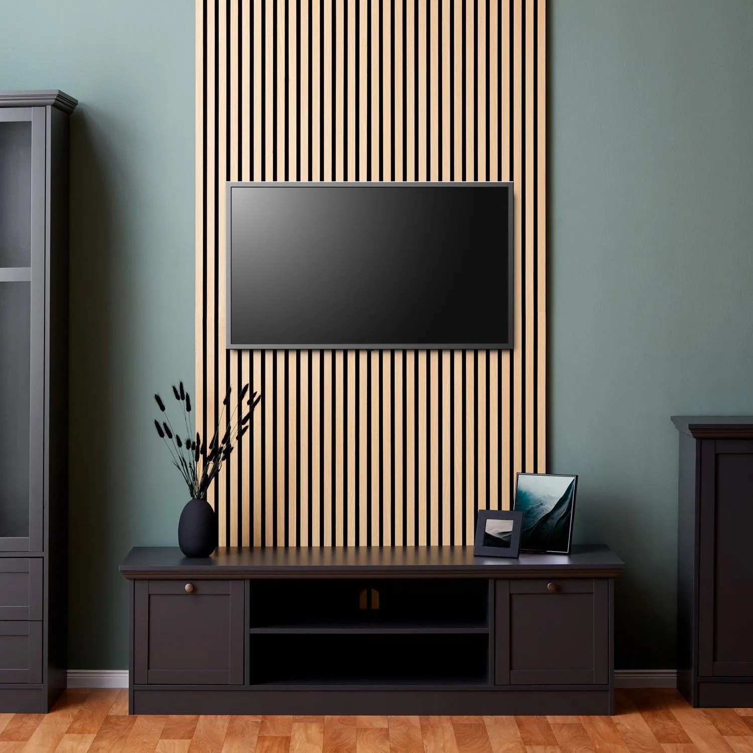 Akustikpaneele Holz 60x60 cm als TV-Wand im Wohnzimmer. Natürliche Holzlamellen auf schwarzem Filz für Schallschutz.