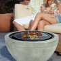 Buschbeck Grill-Feuerschale Madrid 60 mit Grillrost und Paar im Hintergrund.