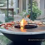 Schwarzer Vente-unique Grill Corvera 81 cm mit Plancha-Ring und Feuerstelle, Gemüse wird gegrillt.