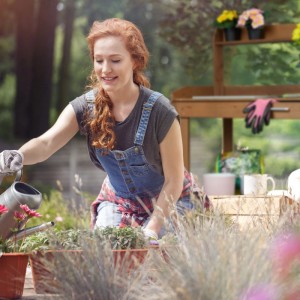Junge Frau gießt Pflanzen an einem braunen Relaxdays Pflanztisch aus Holz. Perfekt für die Gartenarbeit.