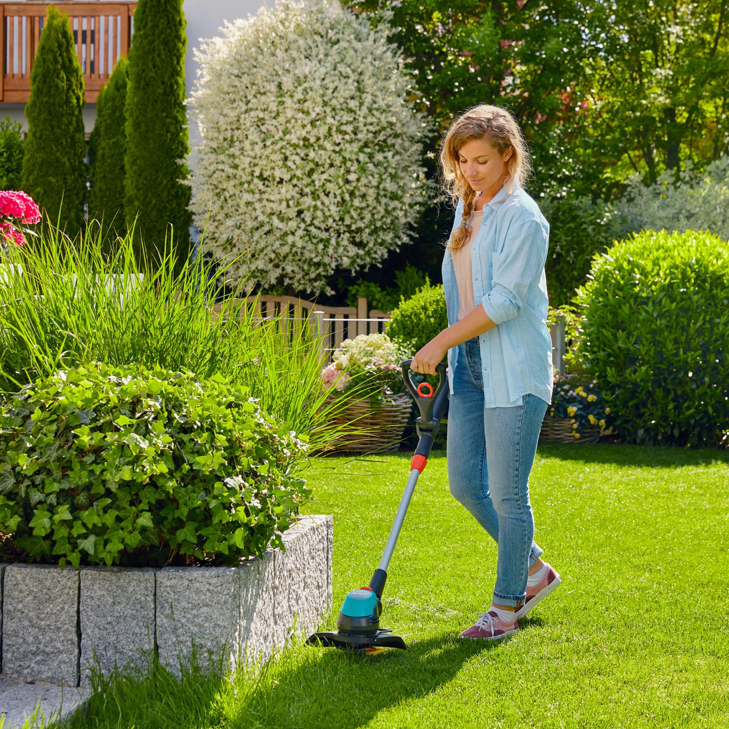 Frau trimmt Rasen mit Gardena Akku-Trimmer EasyCut 23/18V. Inkl. Akku-Set.