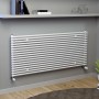 Weißer Ximax Raumheizkörper Gamba Slim (610x1000 mm) mit horizontalen Rundrohren an grauer Wand.
