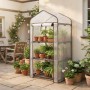 Kompaktes Foliengewächshaus mit transparentem Gitterfolie, dunklem Stahlrahmen und 3 Etagen voller Pflanzen auf Terrasse. Für Balkon & Garten.