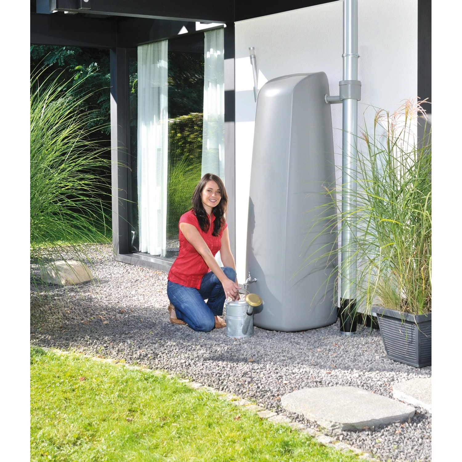 Garantia Regenwasser-Wandtank Elegance 400 l steingrau mit Frau und Gießkanne im Garten.