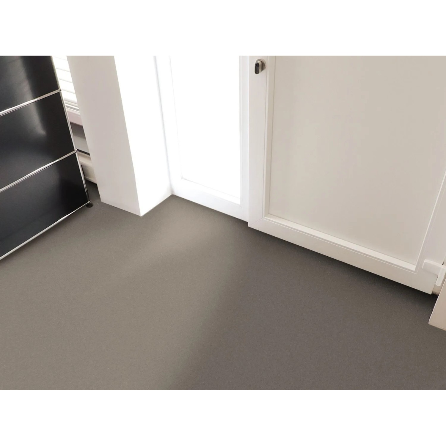Grauer Primaflor PVC Expotop Bodenbelag, unifarben, in einem Raum mit weißen Wänden und Tür. Strapazierfähig.