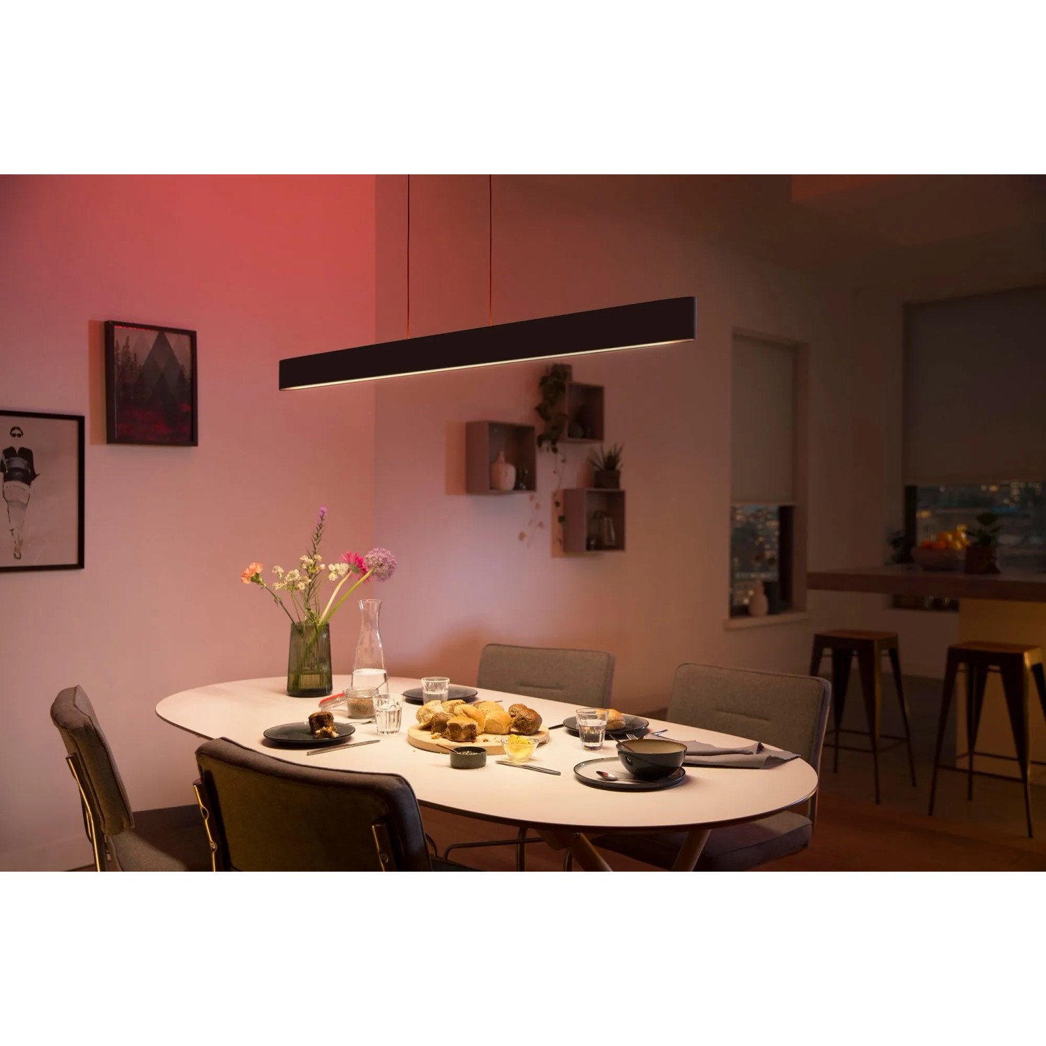 Schwarze Philips Hue Ensis LED-Pendelleuchte über Esstisch mit Speisen und Getränken.
