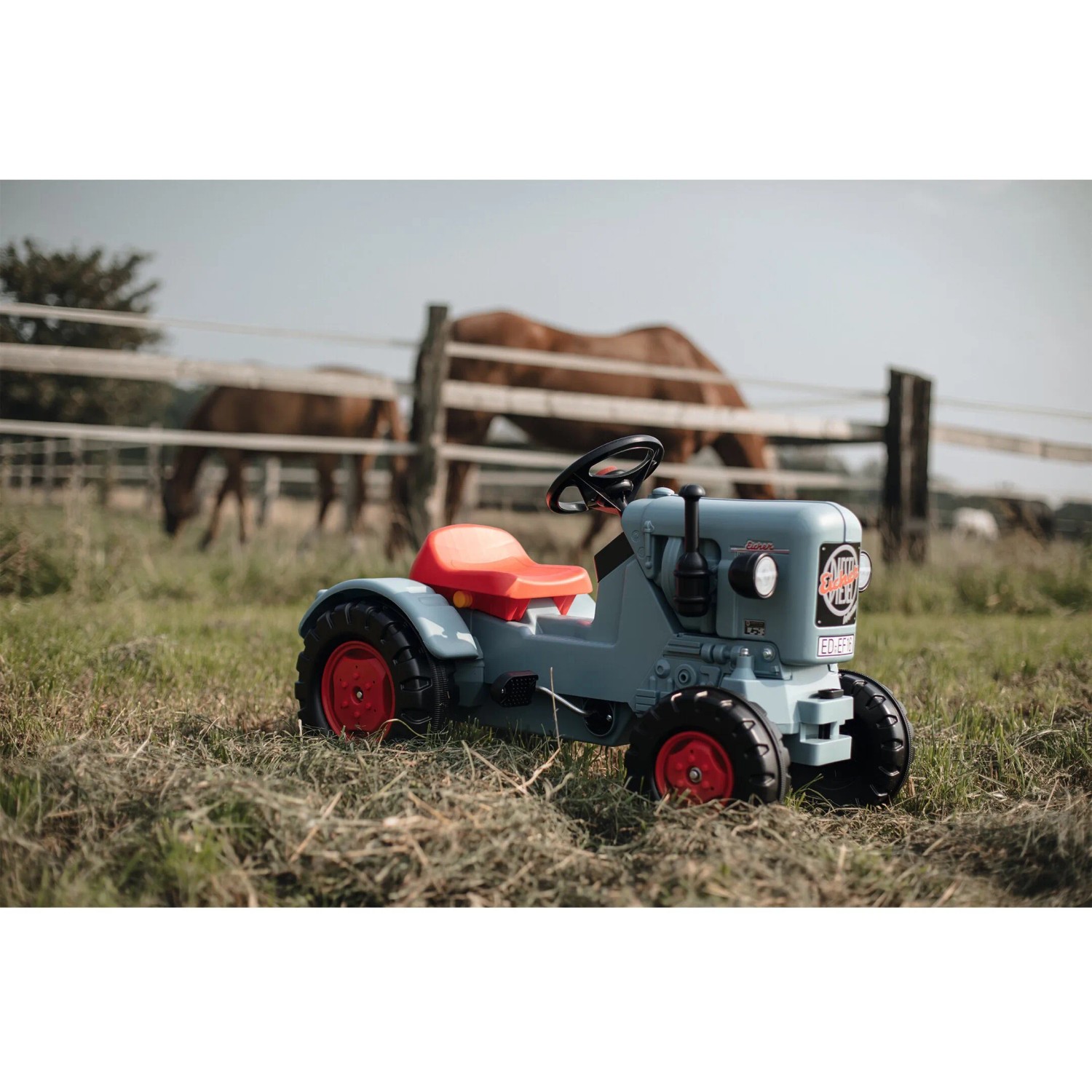 BIG Traktor Eicher Diesel ED 16 Trettraktor im Feld, grauer Korpus, roter Sitz und rote Felgen.