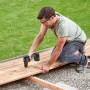 Mann schraubt mit Bosch 18V Akku-Bohrschrauber UniversalDrill 18V-60 ein Brett fest.