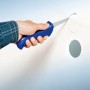 Hand schneidet mit LUX Gipskartonsäge Classic ein Loch in eine weiße Gipskartonwand.