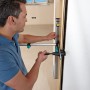 Mann montiert Türfutter mit Wolfcraft Montage-Set Pro. Spannwerkzeug für präzisen Einbau.