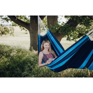 Frau liest in blauer Amazonas Hängematte Santana im Garten.