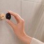 Montage eines schwarzen, matten Tesa Handtuchhakens Moon an einer Badezimmerwand.