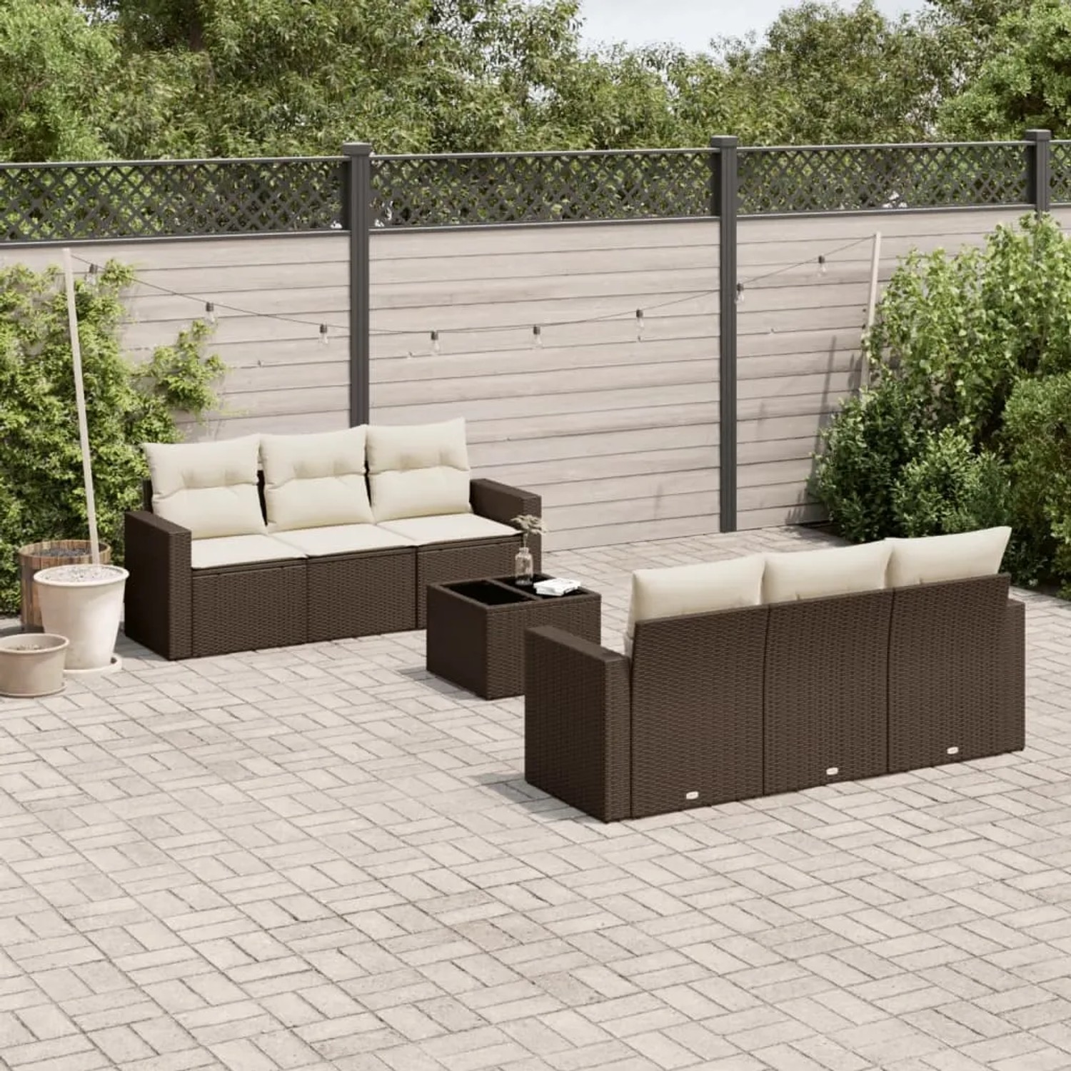 Braune 7-tlg. vidaXL Garten-Sofagarnitur aus Poly Rattan mit cremeweißen Kissen im Garten.