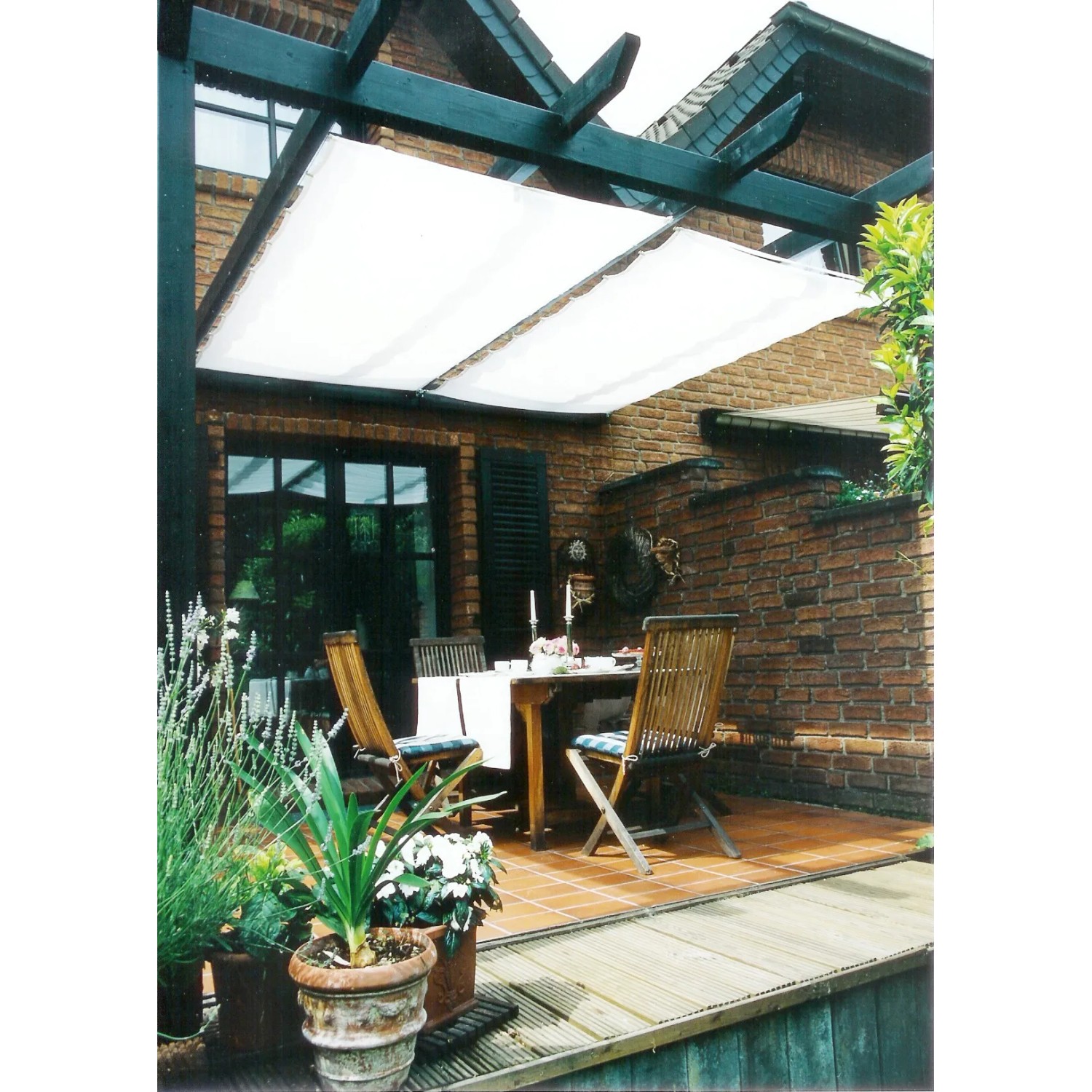 Weißes Peddy Shield Sonnensegel (330x61cm) über einer Terrasse mit Sitzgruppe.