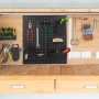 Schwarze Relaxdays Werkzeugwand aus Stahl, 9-teilig, mit Haken und Boxen, montiert über einer Werkbank zur Werkzeugaufbewahrung.