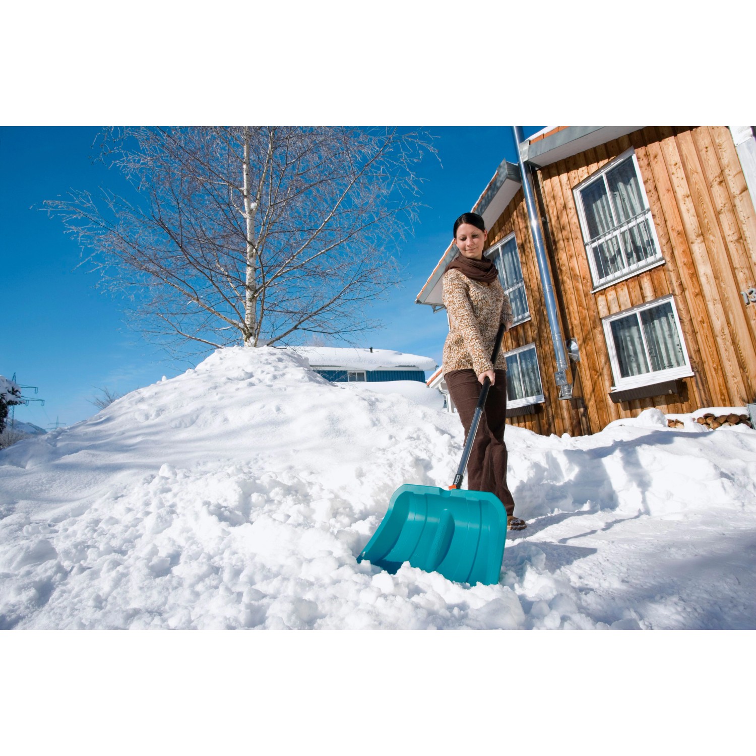 Frau schiebt Schnee mit dem Gardena combisystem Schneeschieber ES 40 cm.