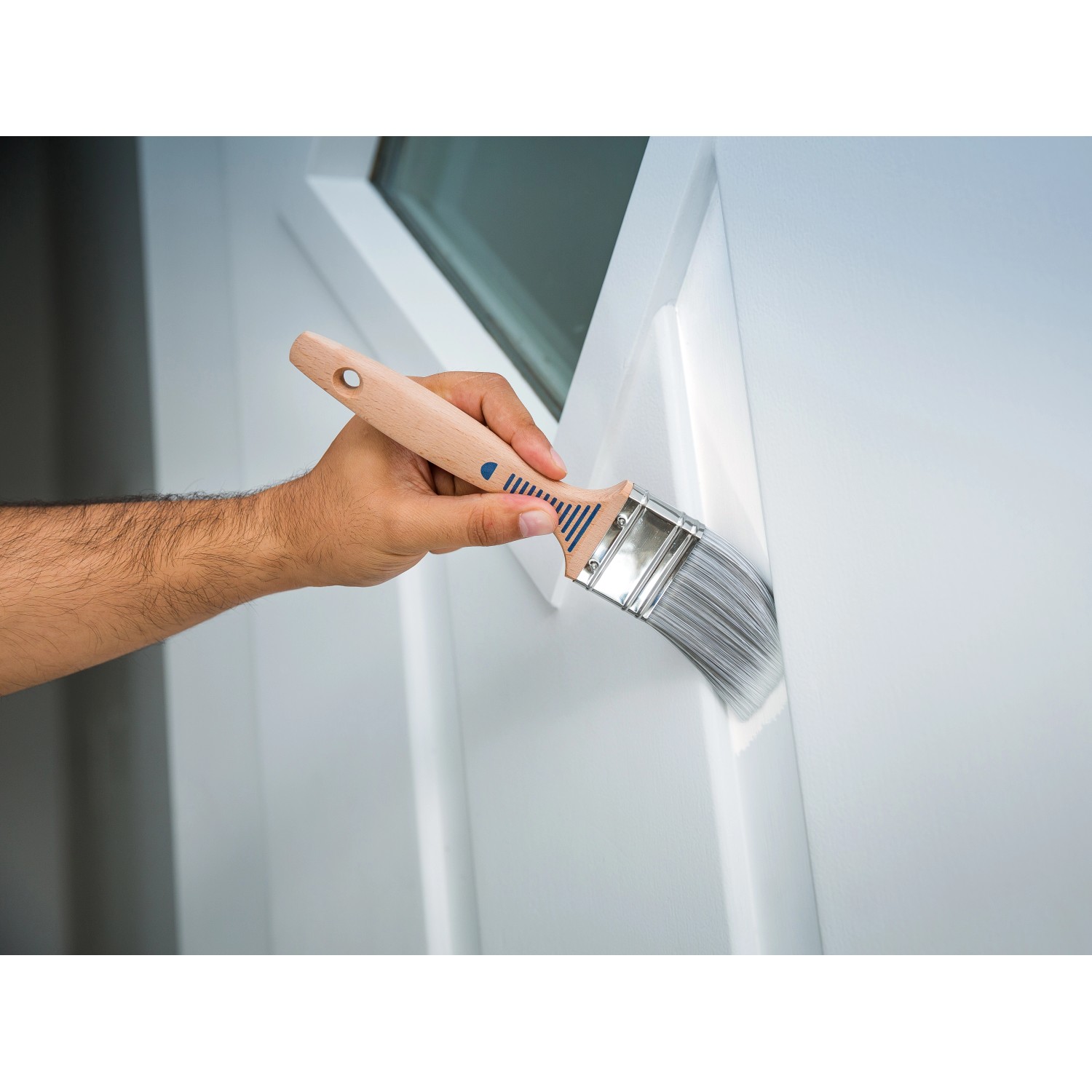 Lackierarbeiten mit LUX Flachpinsel 30 mm. Hand mit Pinsel beim Streichen einer Tür.