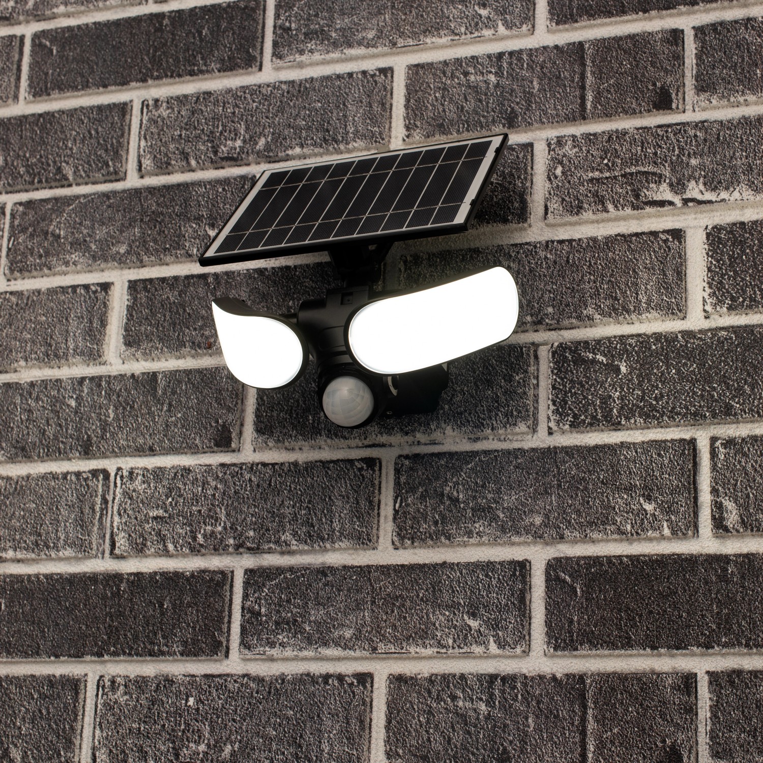LED-Solar-Außenleuchte Botshabelo mit Sensor an grauer Backsteinwand. Solar-Wandleuchte mit Bewegungsmelder.